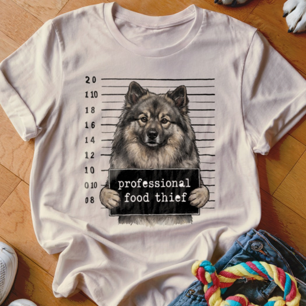 Keeshond mugshot on a t-shirt reading "professional food thief".