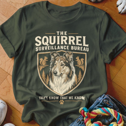 Dark green t-shirt with a vintage-style graphic featuring a rough collie and text reading The Squirrel Surveillance Bureau.