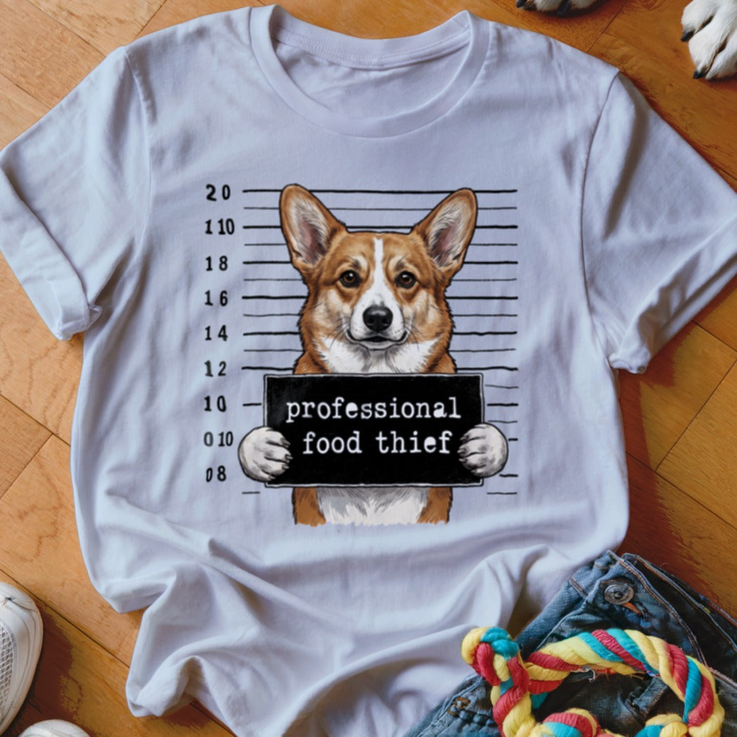 Corgi dog in mugshot holding "professional food thief" sign.