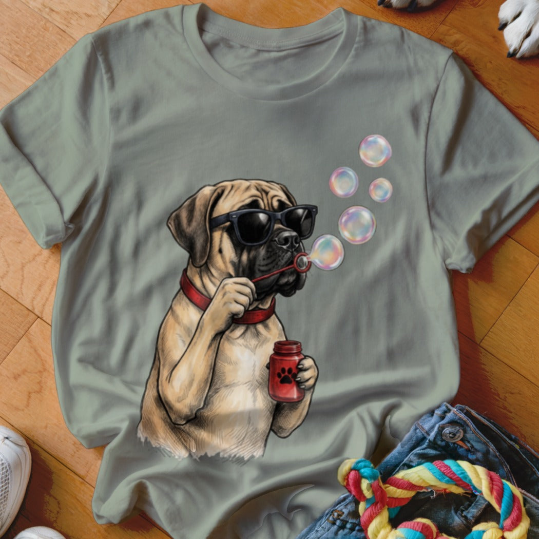 A sage green t-shirt featuring a graphic of a mastiff wearing sunglasses and blowing soap bubbles.