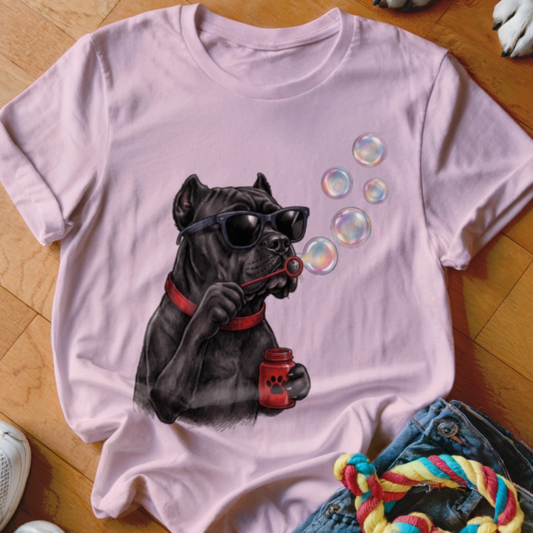 A light pink t-shirt featuring a graphic of a black dog wearing sunglasses and blowing soap bubbles.