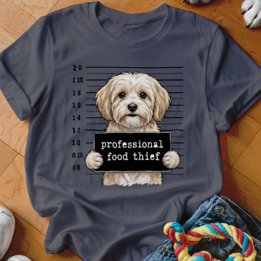 Fluffy dog in mugshot holding "professional food thief" sign.
