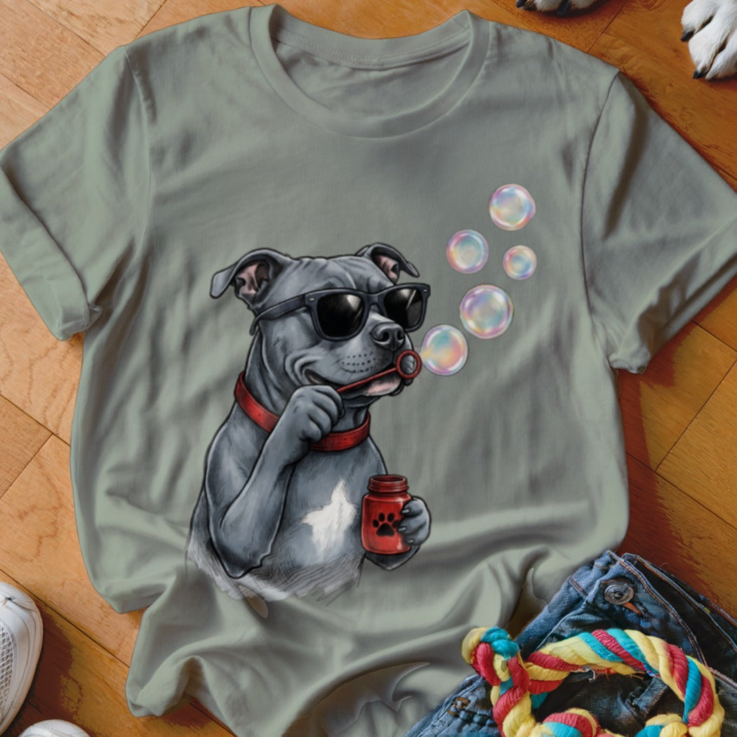 Sage green t-shirt featuring a graphic of a grey dog wearing sunglasses and blowing bubbles.