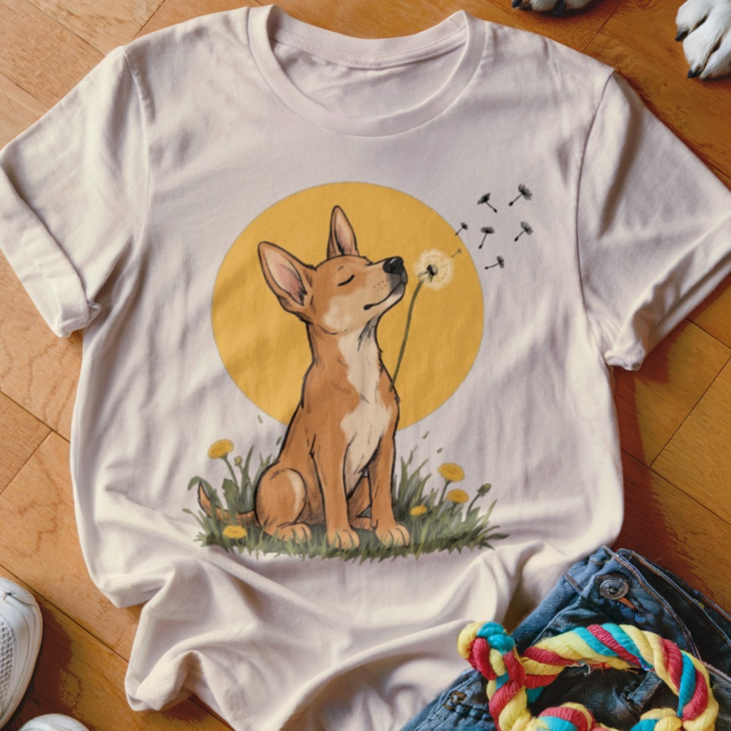 A light beige t-shirt featuring a cartoon illustration of a dog blowing dandelion seeds.