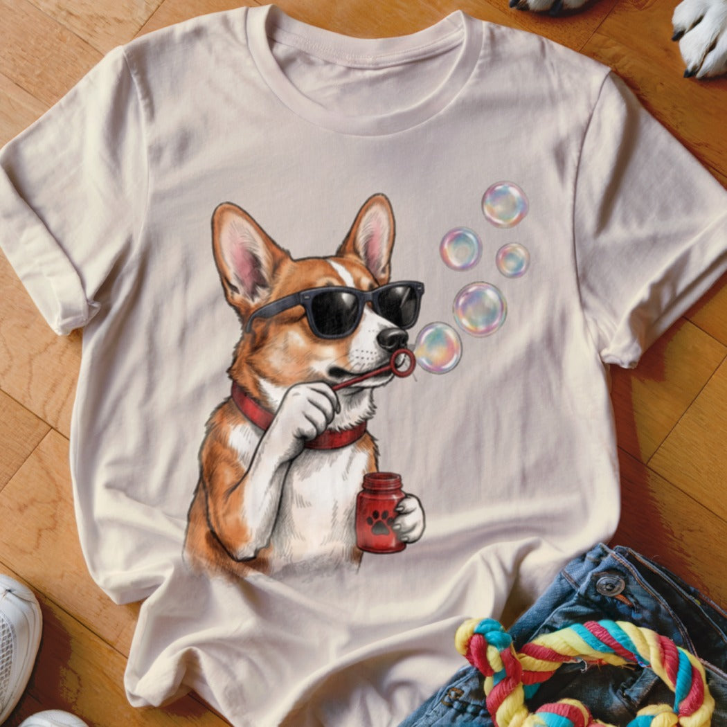 Light-colored t-shirt featuring a cartoon corgi wearing sunglasses and blowing soap bubbles.
