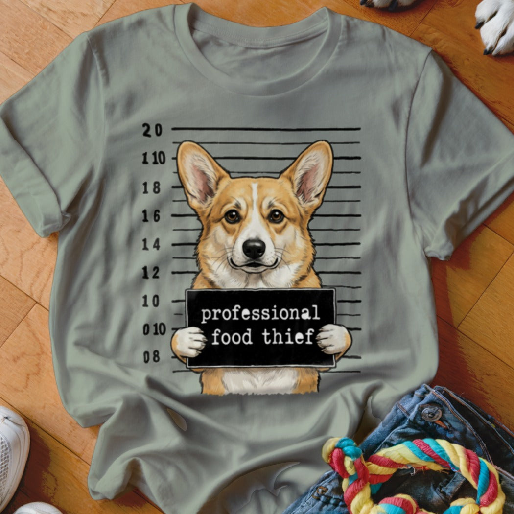 Corgi wearing a mugshot sign that reads "professional food thief".