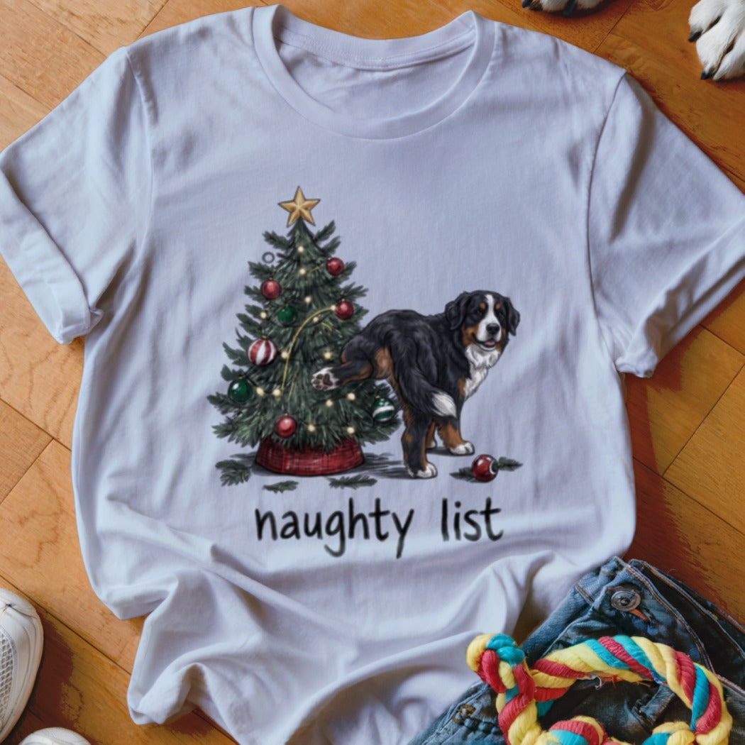 White t-shirt featuring a Bernese Mountain Dog lifting its leg on a Christmas tree with the text "naughty list".