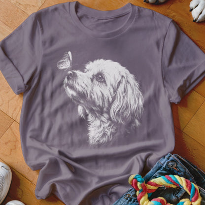 A purple crewneck t-shirt featuring a white graphic of a shaggy dog looking at a butterfly.