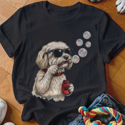 A black t-shirt printed with a fluffy white dog wearing sunglasses and blowing soap bubbles.