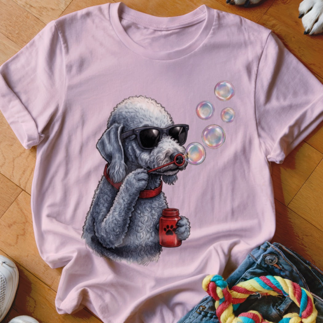 A pink t-shirt features a graphic of a grey poodle wearing sunglasses and blowing bubbles.