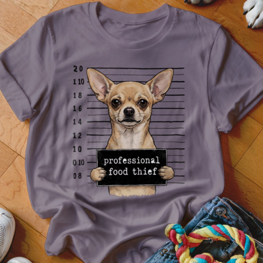 Chihuahua in mugshot holding a sign that reads "professional food thief".