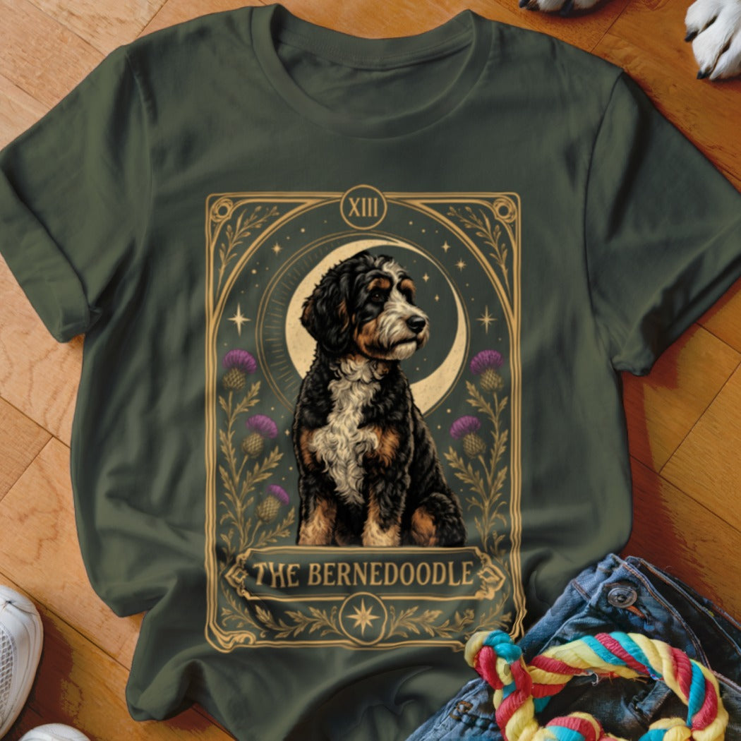 Dark green t-shirt featuring a tarot card graphic of a Bernedoodle surrounded by thistles.