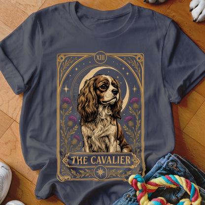 A dark grey crewneck t-shirt featuring a tarot card graphic of a Cavalier King Charles Spaniel with the text "THE CAVALIER".