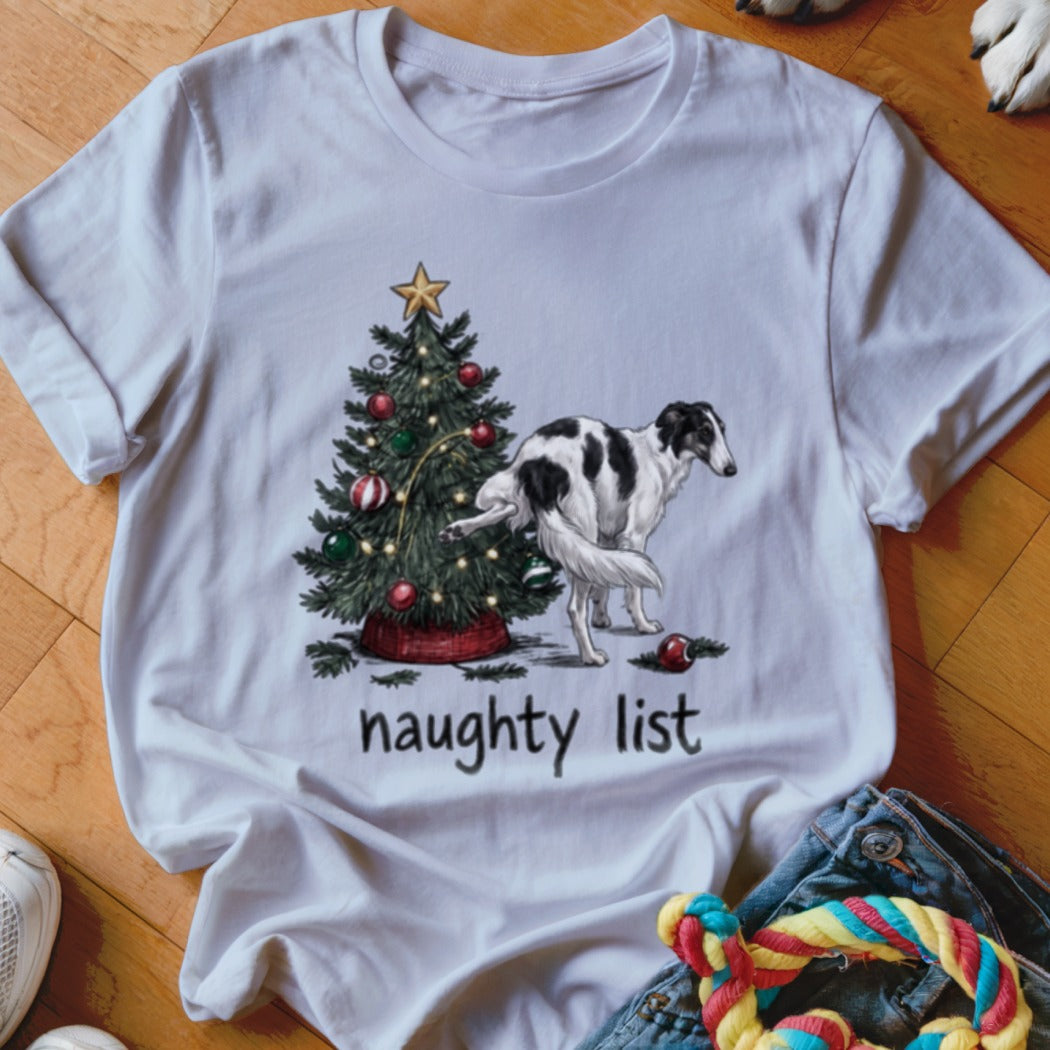 A white t-shirt featuring a graphic of a borzoi dog lifting its leg on a Christmas tree with the text "naughty list" underneath.