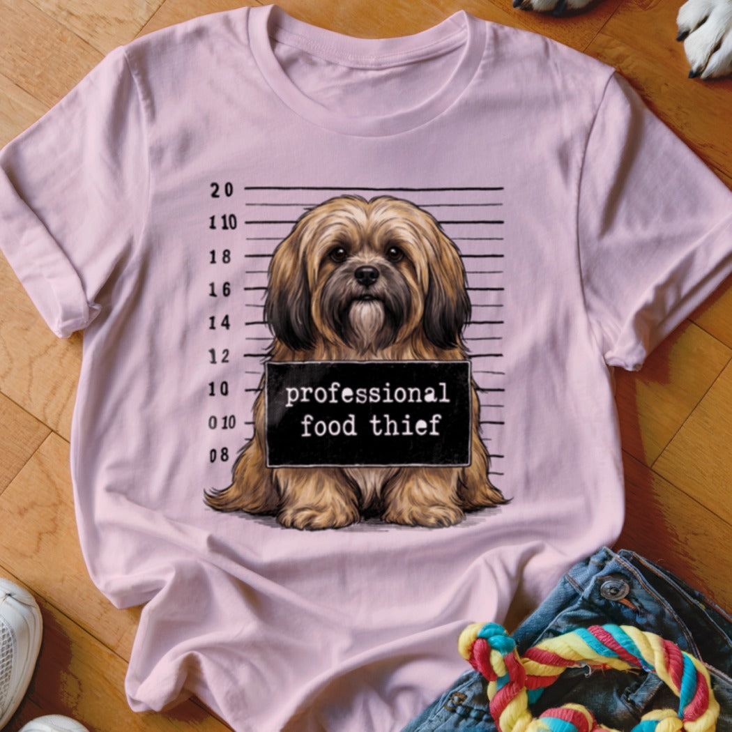 Light pink t-shirt with a dog in a mugshot wearing a "professional food thief" sign.