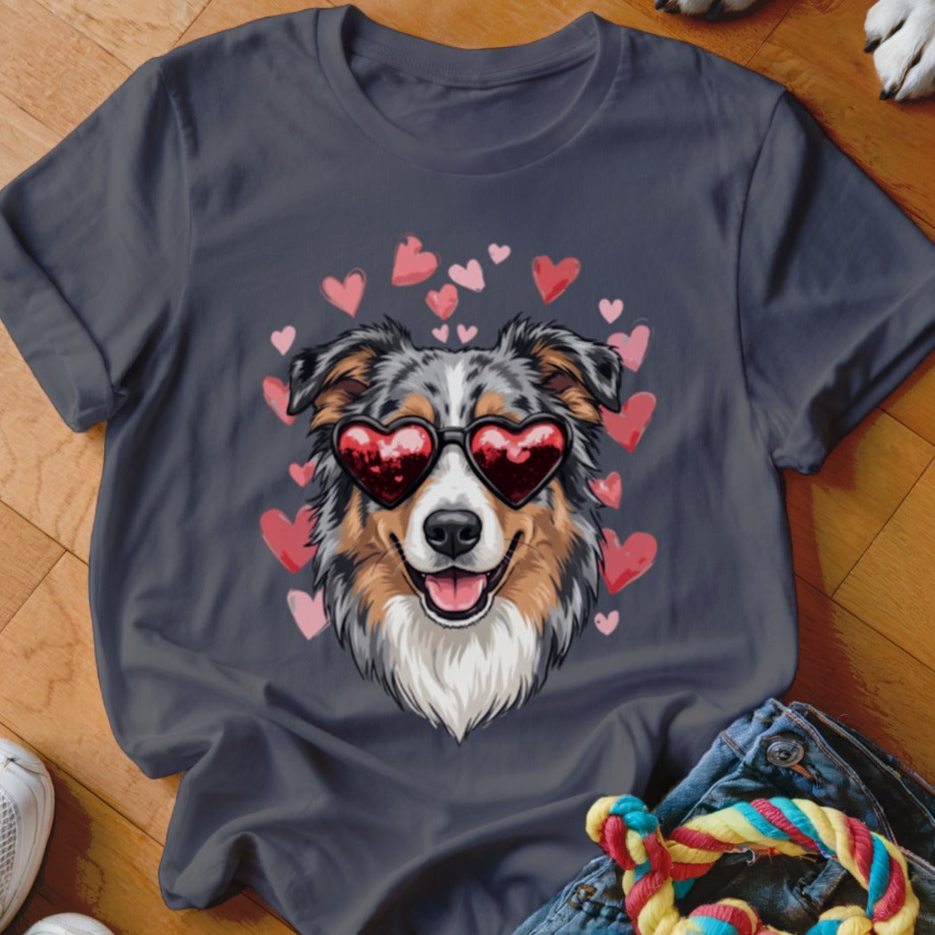 A dark gray t-shirt featuring an illustration of an Australian Shepherd wearing heart-shaped sunglasses surrounded by pink hearts.