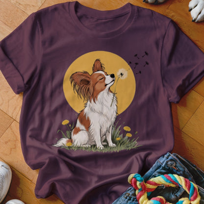Maroon crewneck t-shirt featuring a graphic of a brown and white Papillon dog blowing dandelion seeds against a yellow moon.