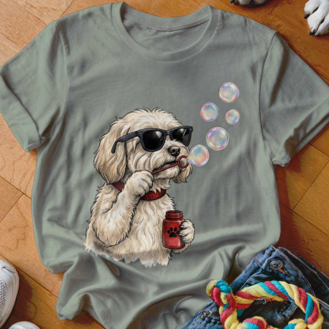Sage green t-shirt featuring a graphic of a white dog wearing sunglasses and blowing bubbles.