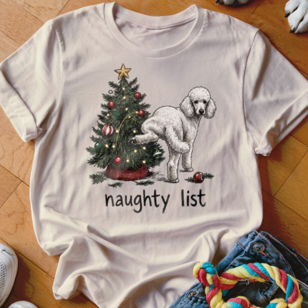 Beige crewneck t-shirt featuring an illustration of a white poodle lifting its leg on a Christmas tree with the text naughty list underneath.