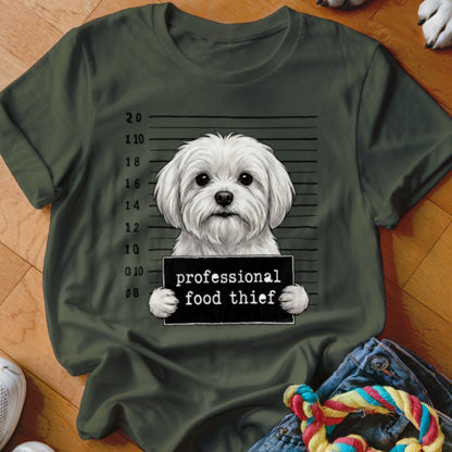 White fluffy dog holding a "professional food thief" sign in front of a mugshot background.