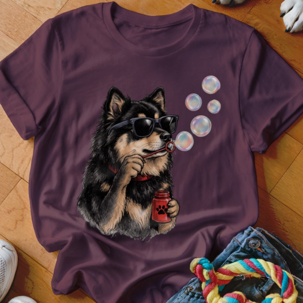A maroon t-shirt featuring an illustration of a black and tan dog wearing sunglasses and blowing bubbles.