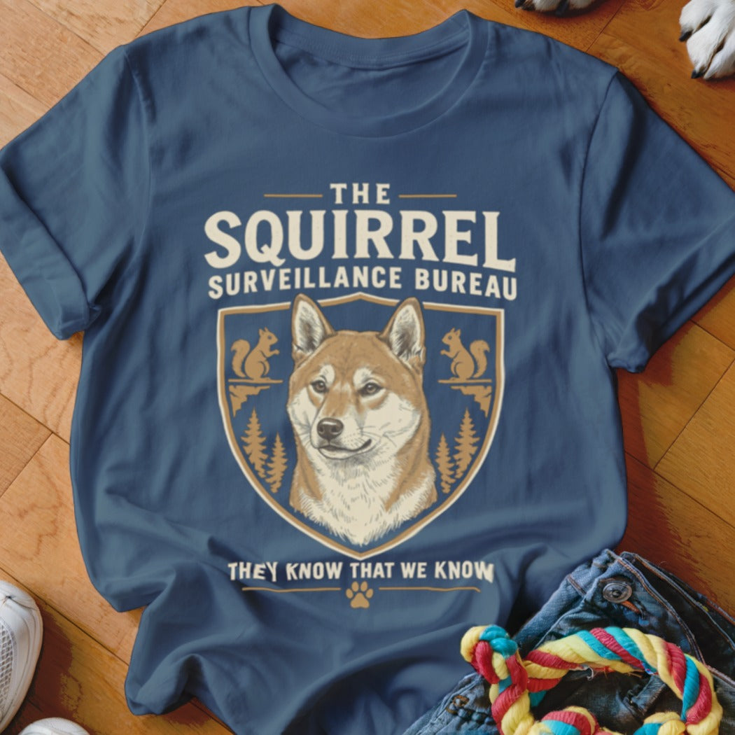 A blue t-shirt featuring a Shiba Inu graphic and the text The Squirrel Surveillance Bureau.