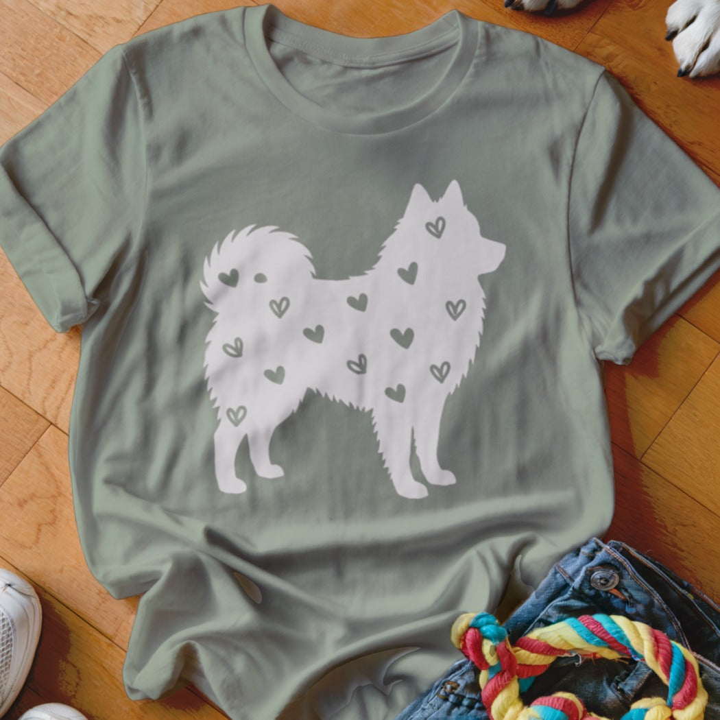 White silhouette of a fluffy dog with scattered small hearts on a light green t-shirt.