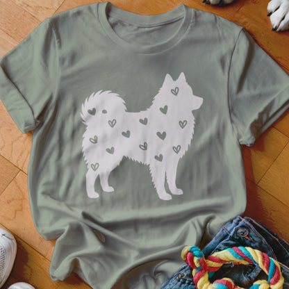 White silhouette of a fluffy dog with scattered small hearts on a light green t-shirt.