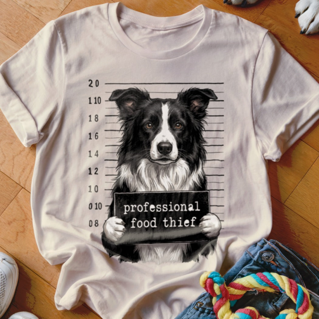 Border collie in mugshot holding sign that reads "professional food thief."