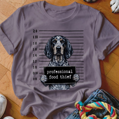 Dog with 'professional food thief' sign in mugshot pose on a t-shirt.