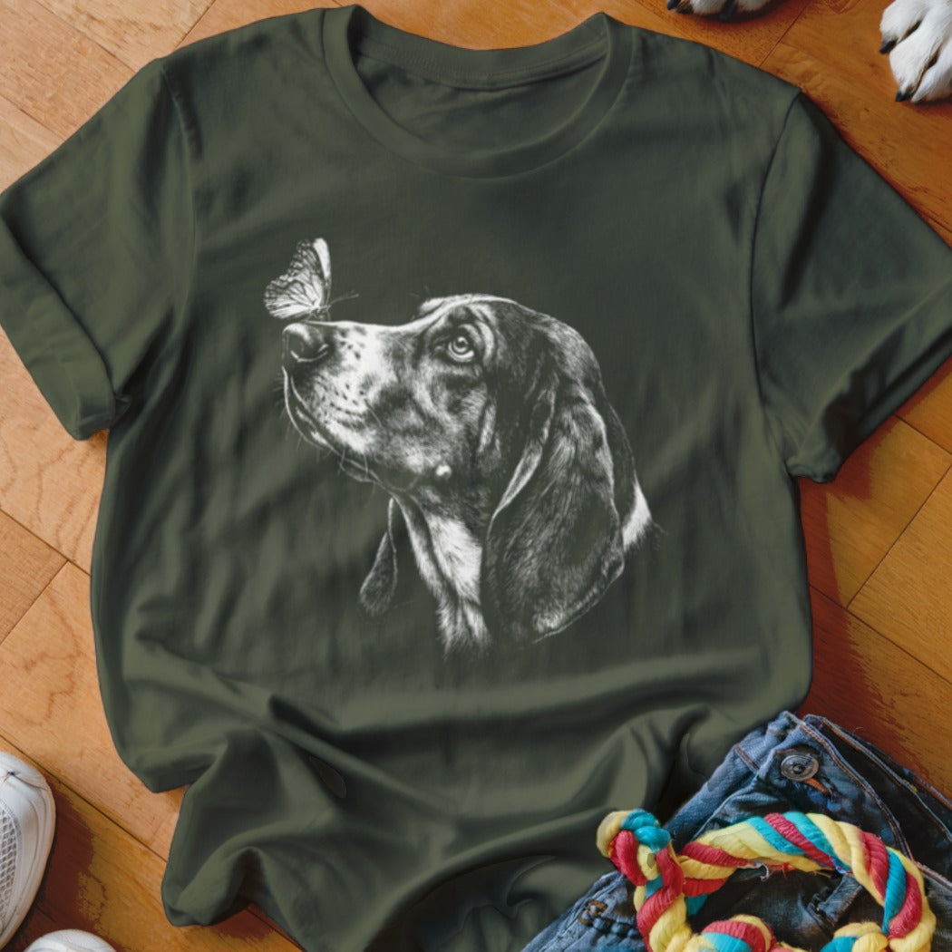 Dark green t-shirt featuring a white sketch of a dog looking at a butterfly on its nose.