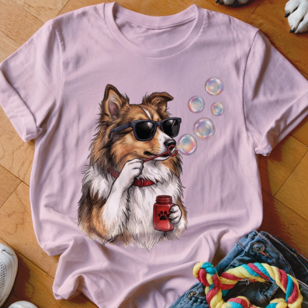 Light pink t-shirt featuring an illustration of a brown dog wearing sunglasses blowing bubbles.