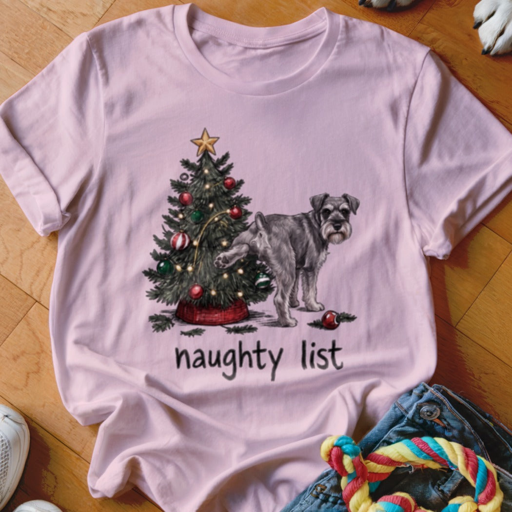 A light pink t-shirt features a graphic of a schnauzer lifting its leg on a Christmas tree, with the text "naughty list" underneath.