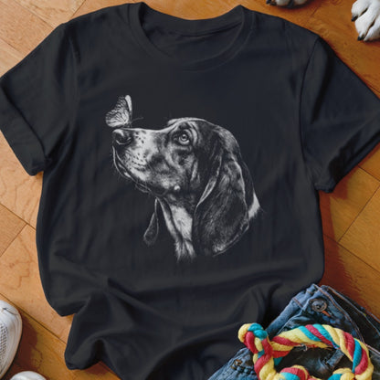 A black t-shirt features a white sketch of a dog looking at a butterfly on its nose.