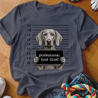 Weimaraner dog mugshot with "professional food thief" sign.