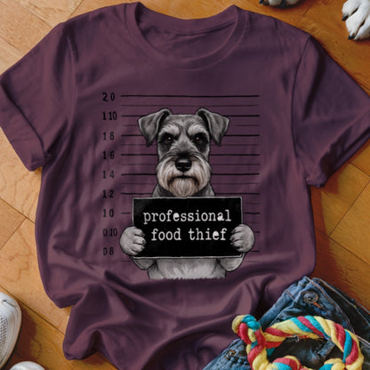 Schnauzer mugshot with "professional food thief" sign on maroon t-shirt.