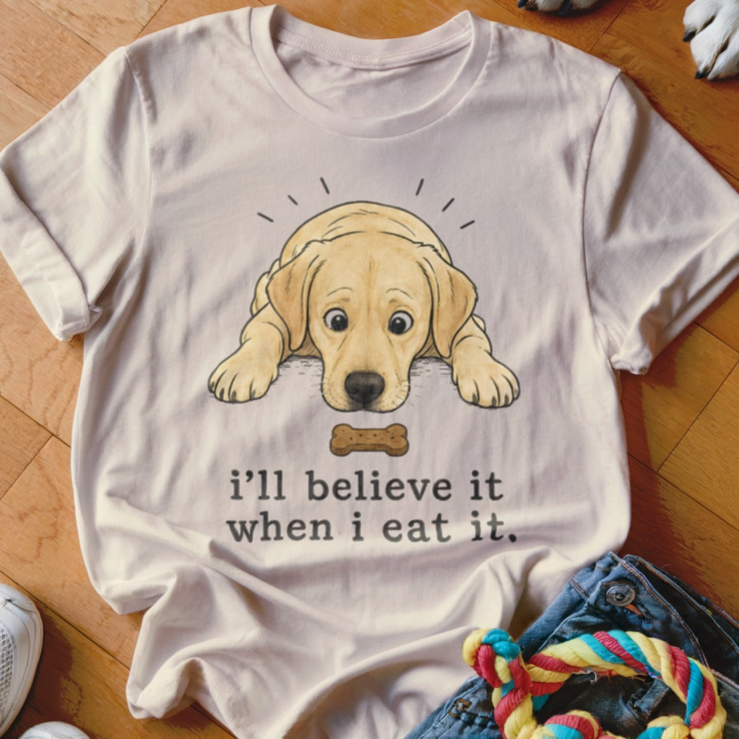 Light-colored t-shirt with a cartoon yellow lab puppy looking at a bone, with text "i'll believe it when i eat it."