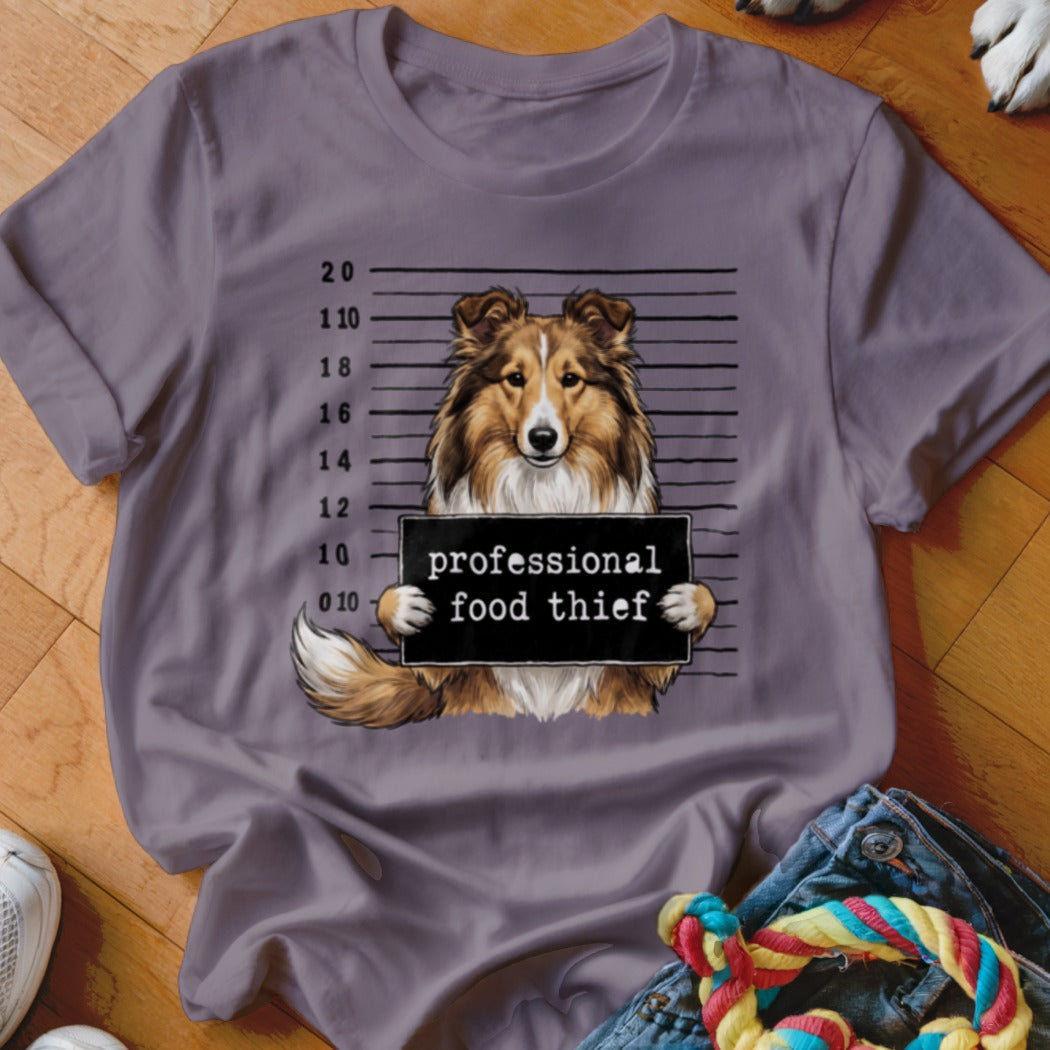 Shetland sheepdog mugshot with "professional food thief" sign.