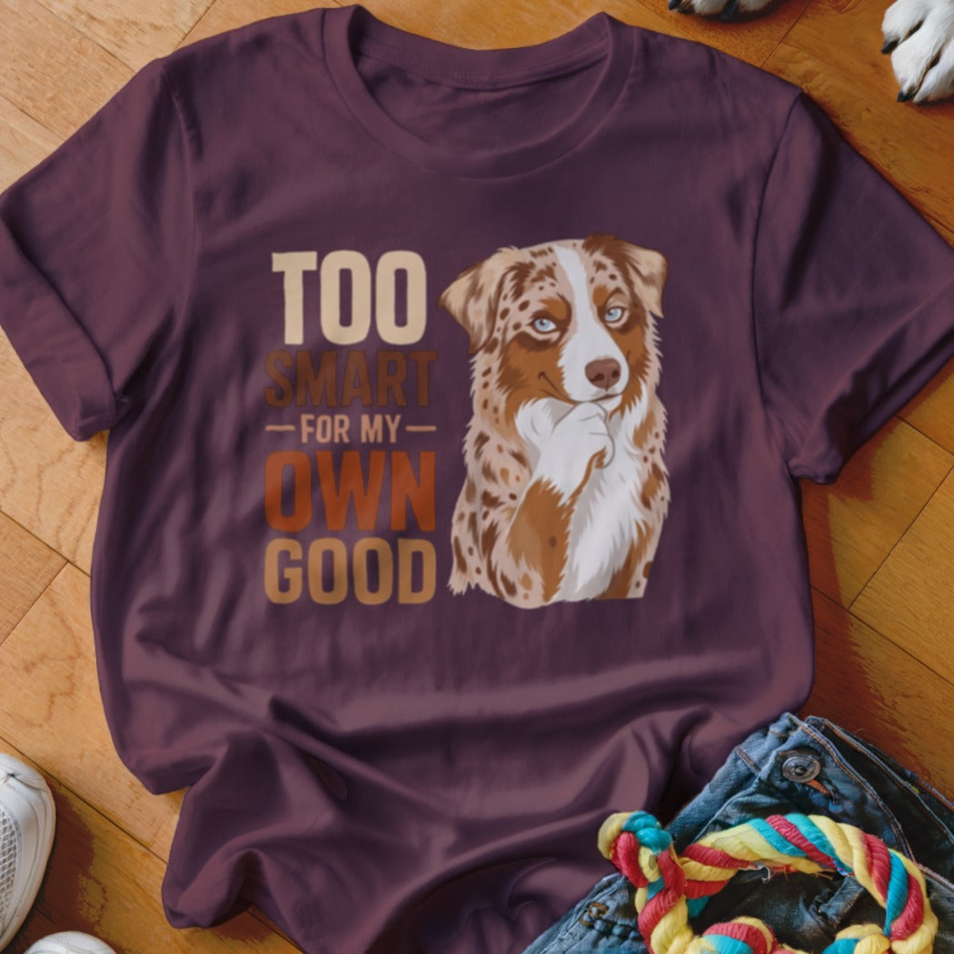 A maroon t-shirt featuring a red merle Australian Shepherd illustration and the text Too Smart For My Own Good.