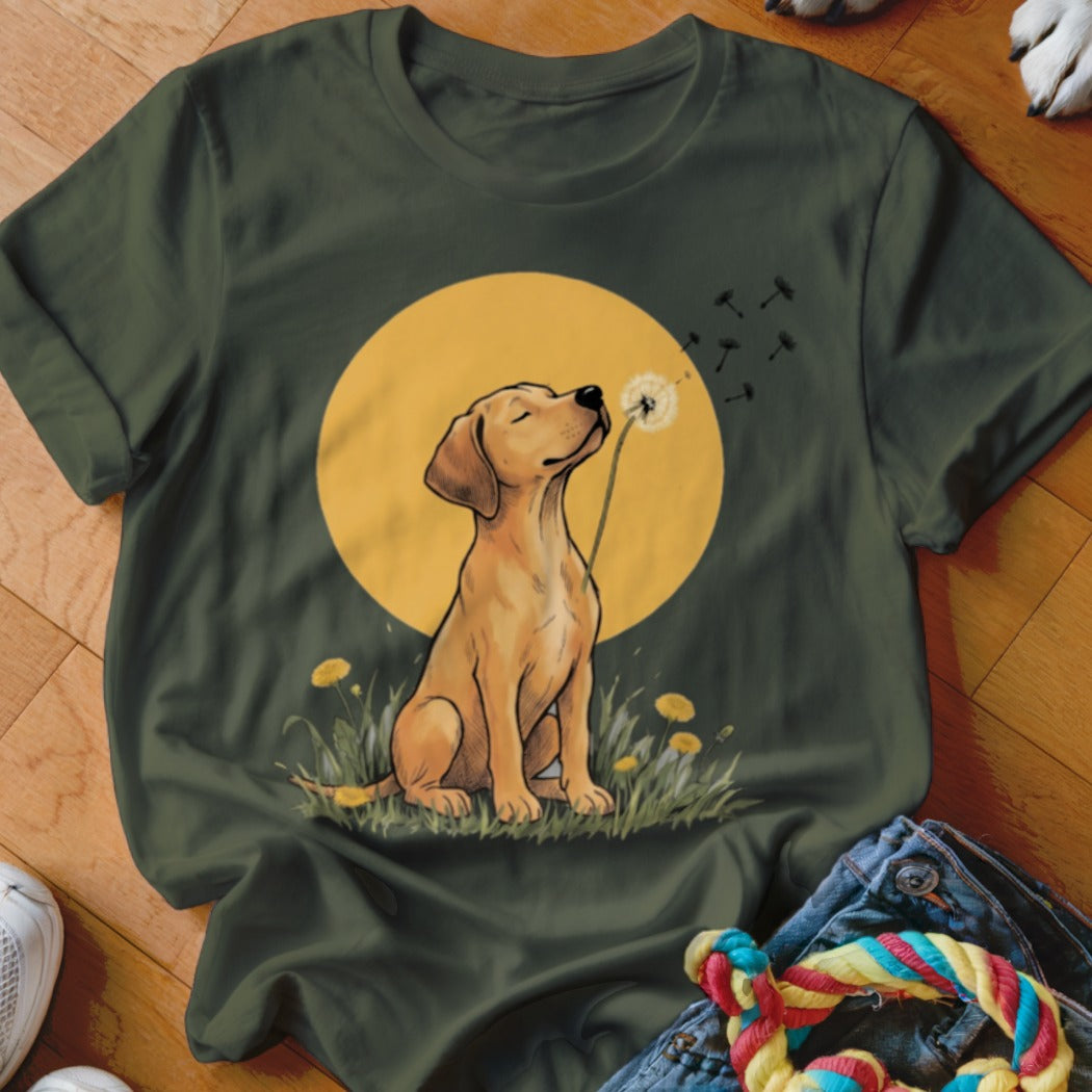Dark green t-shirt featuring a graphic of a golden puppy blowing a dandelion against a yellow sun.
