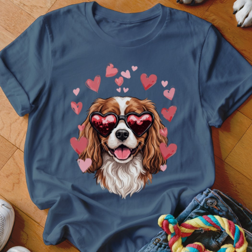 A dark blue t-shirt printed with a Cavalier King Charles Spaniel wearing heart-shaped sunglasses surrounded by pink hearts.