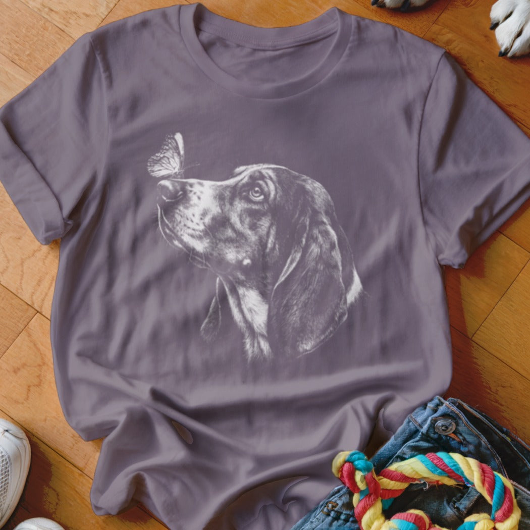 A purple t-shirt featuring a white graphic of a hound looking at a butterfly on its nose.