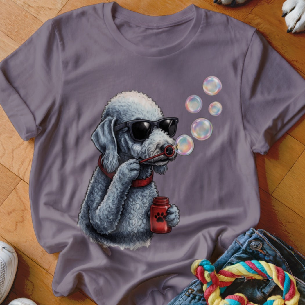 A grey crewneck t-shirt featuring a graphic of a grey poodle wearing sunglasses and blowing bubbles.