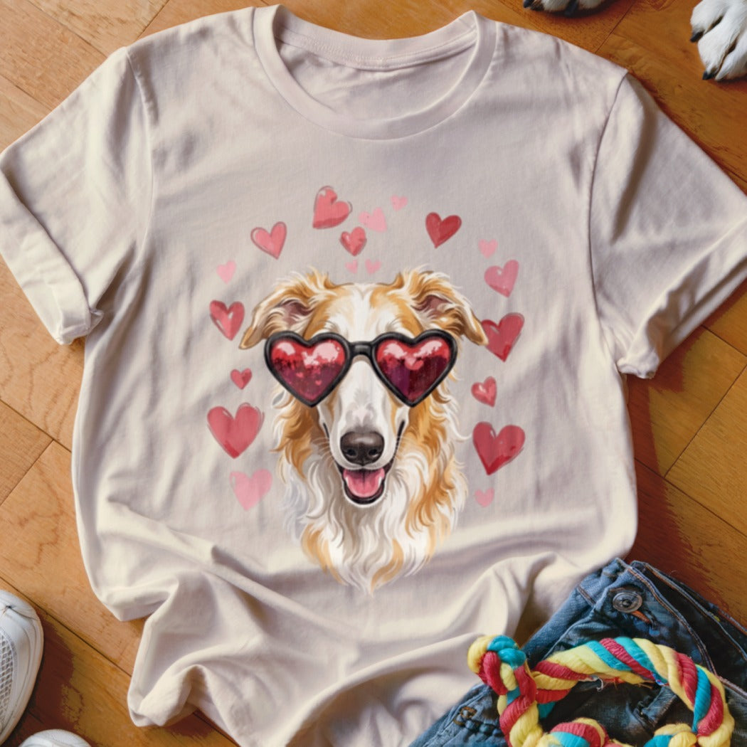 A light-colored t-shirt featuring a graphic of a long-haired dog wearing heart-shaped sunglasses surrounded by floating pink hearts.