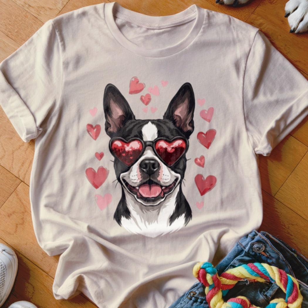 A light-colored t-shirt featuring a graphic of a Boston Terrier wearing heart-shaped sunglasses, surrounded by pink hearts.