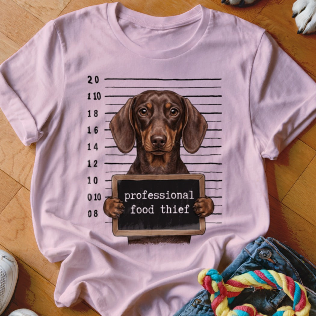 Dachshund mugshot graphic on pink t-shirt with "professional food thief" text.