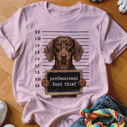 Dachshund mugshot graphic on pink t-shirt with "professional food thief" text.
