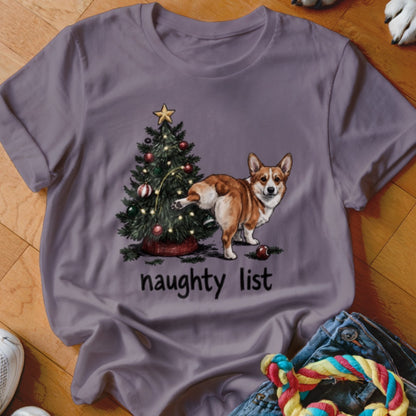 Corgi near a Christmas tree with "naughty list" text on a purple t-shirt.