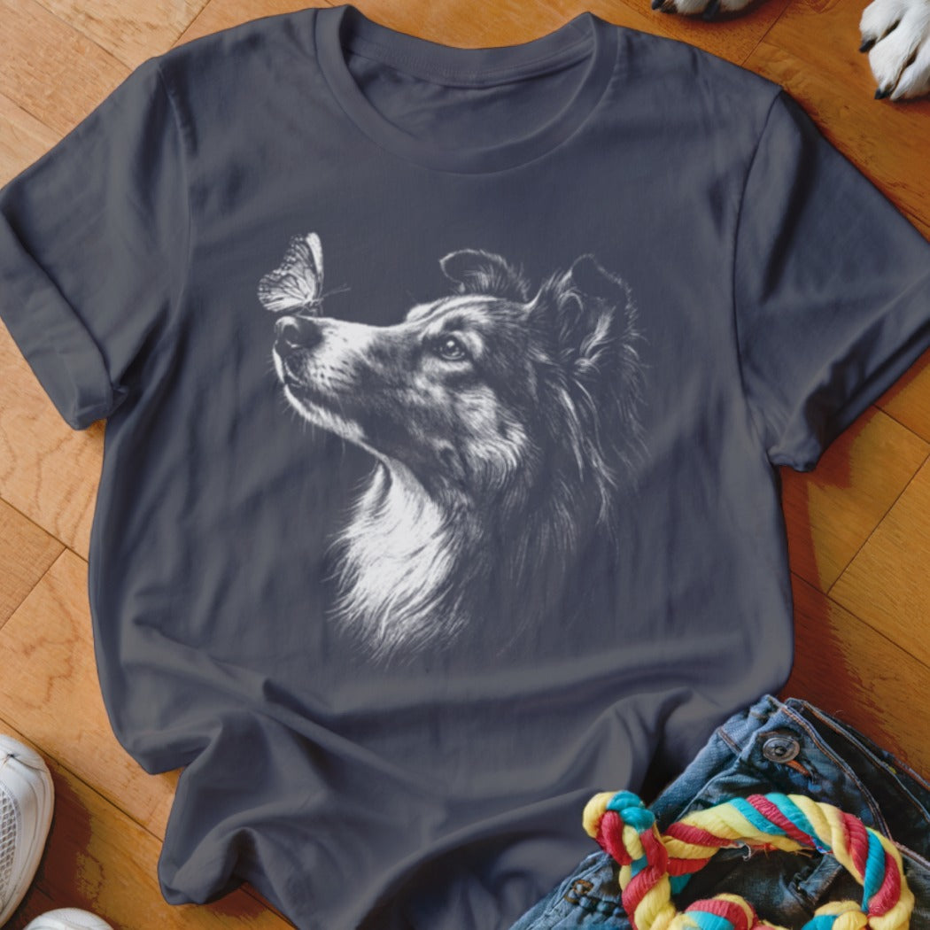 A dark grey t-shirt featuring a white sketch of a collie looking at a butterfly.