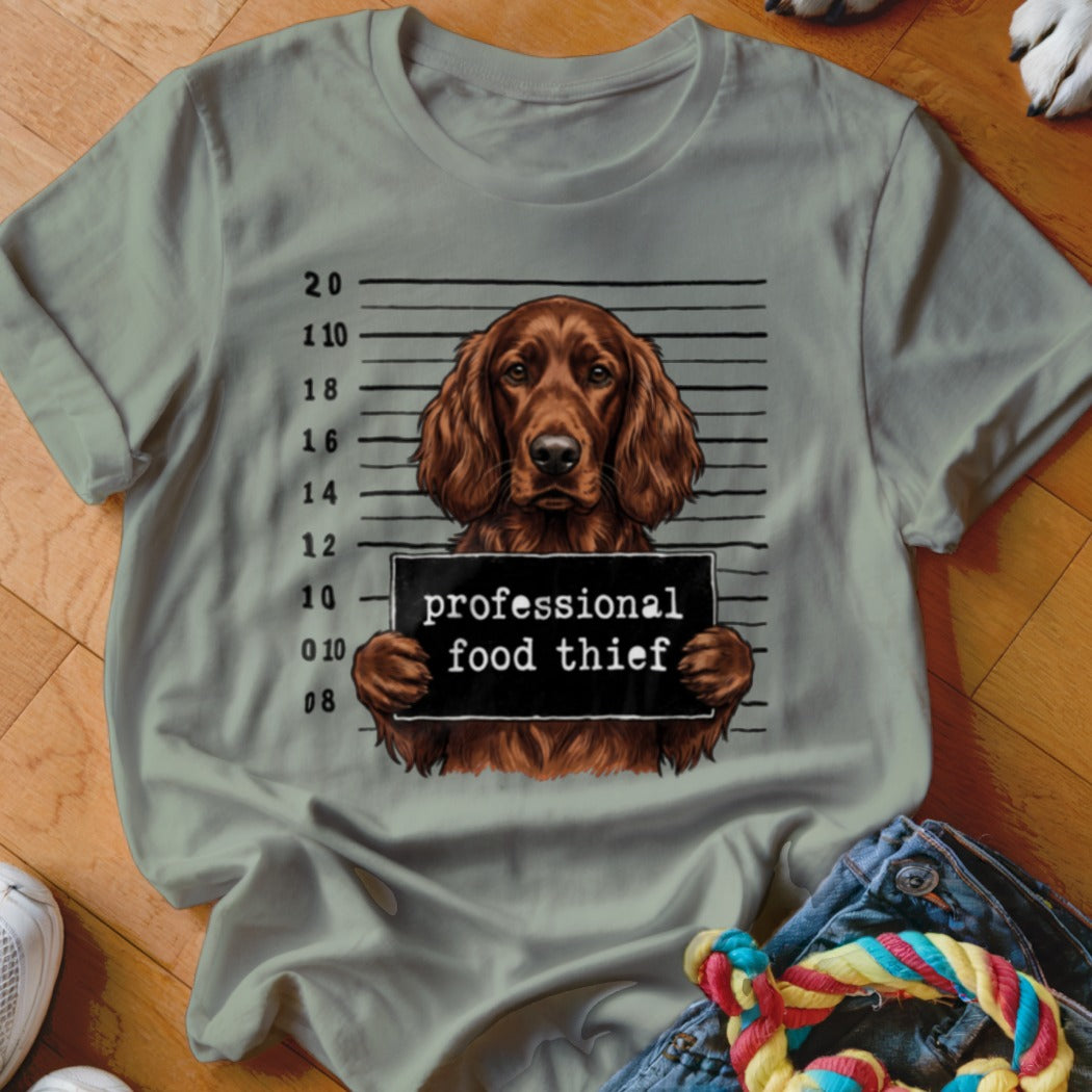 Brown dog in mugshot holding "professional food thief" sign.